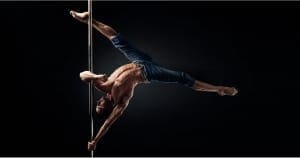 male pole dancer in jeans poses on the pole