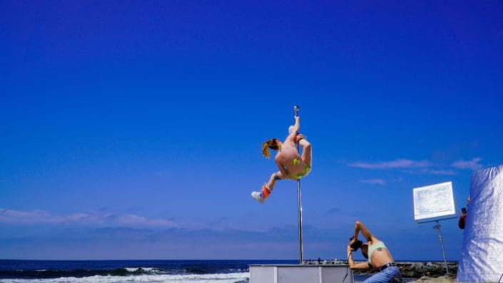 Photographer shoots pole dancer doing splits on an all star stages portable dance pole on the beach CU 3-2 Photographer shoots pole dancer doing splits on an all star stages portable dance pole on the beach CU 3-2