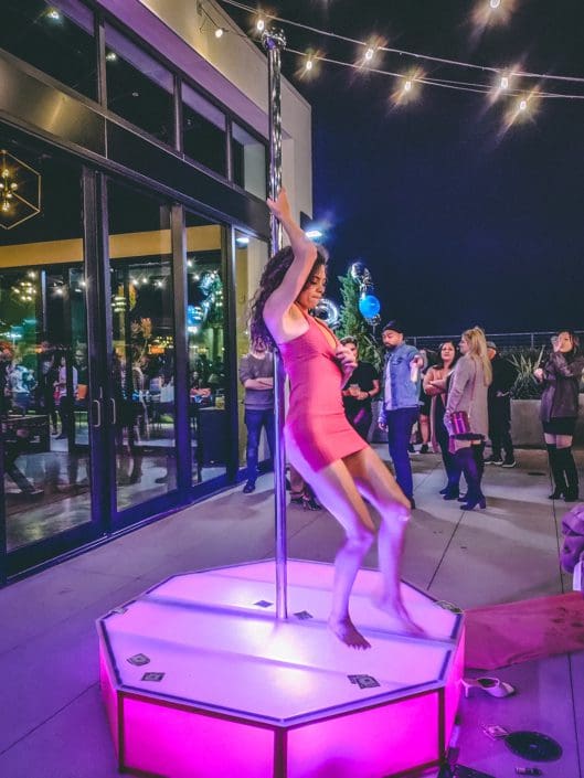 girl dances on all star stages pink delight outside with dollars on the portable stripper pole stage and pole 1000px