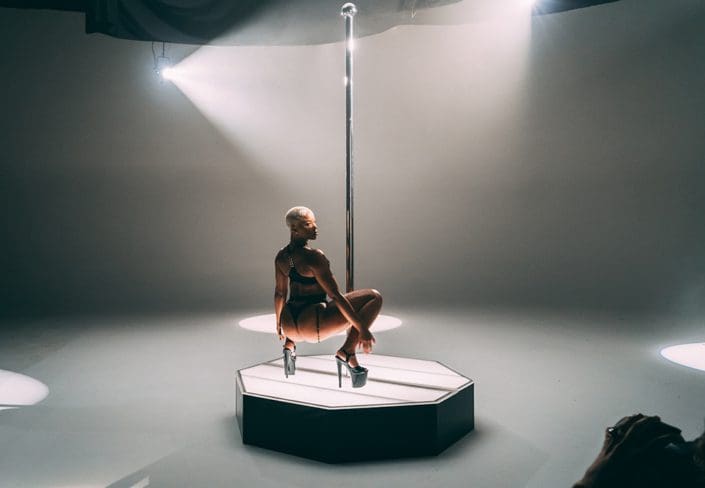 model being photographed in high heels on all star stages portable stripper pole with black side kits 1000px