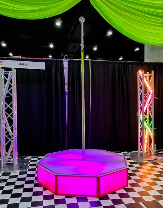 pink all star stages portable stripper pole stage at ru paul expo in awhora booth with checkered floor 1000px