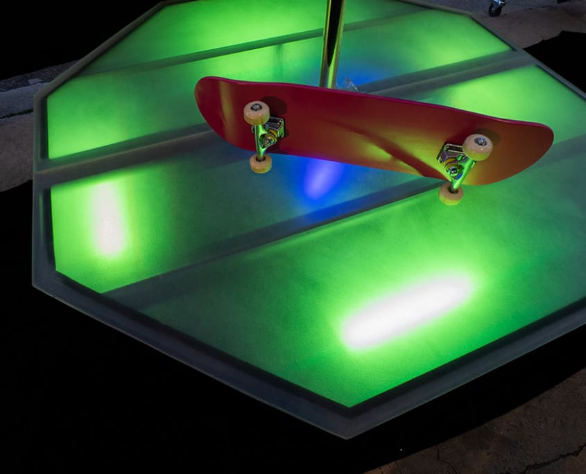 All Star Stages X Brass 45mm spinning dance pole and octagon stage glowing bright green with shot down on the stage and a pink skateboard on top All Star Stages X Brass 45mm spinning dance pole and octagon stage glowing bright green with shot down on the stage and a pink skateboard on top